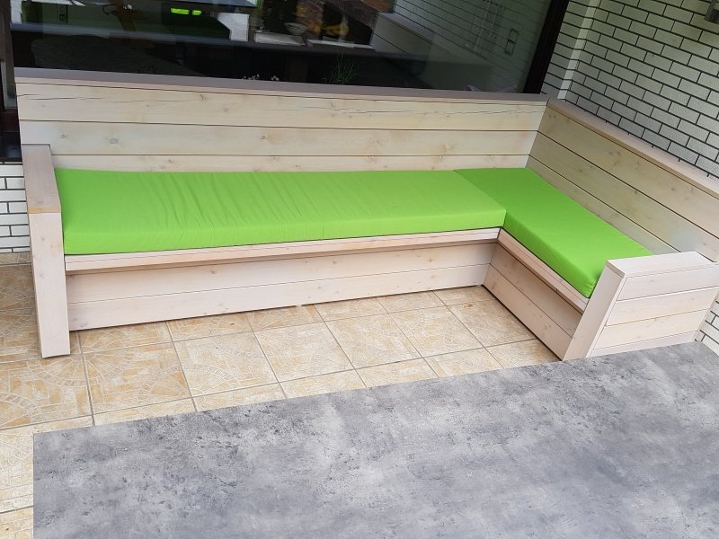 Weiße Gartenbank über Eck mit grünen Polstern und Stauraum