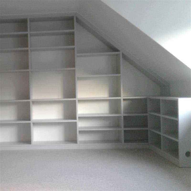 Weiße Regalwand, die exakt in eine Dachschräge eingepasst ist